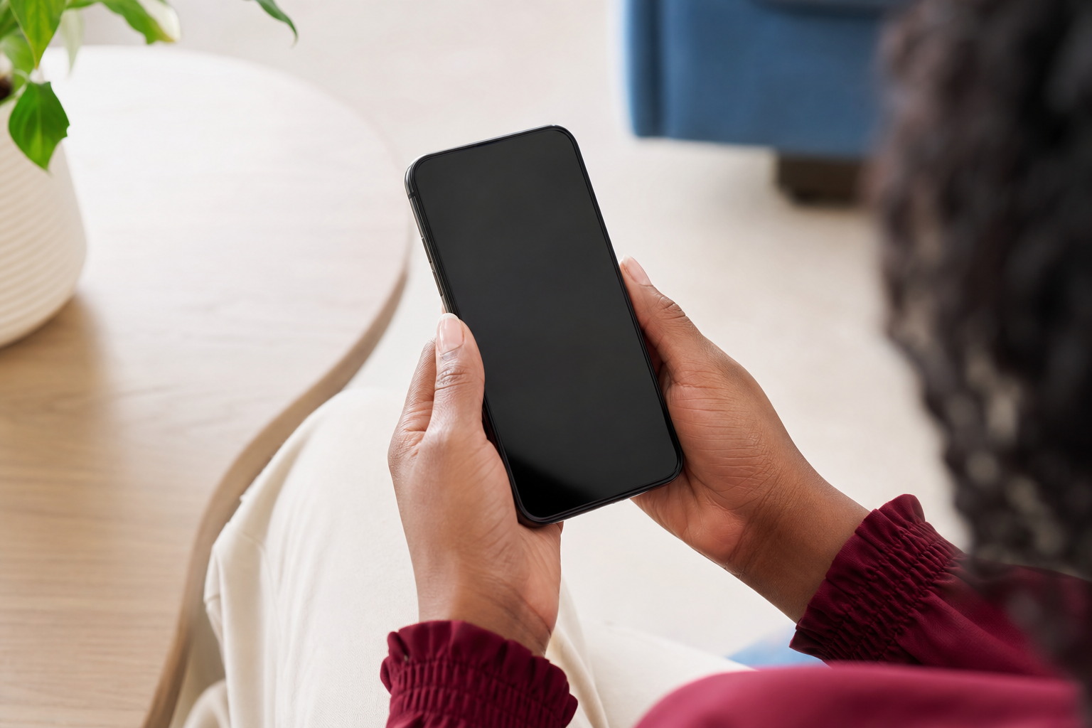 Mãos seguram um celular em um ambiente claro.